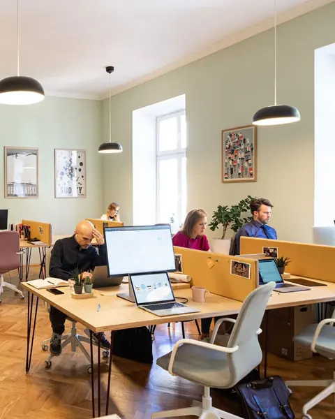 Gründerinnen und Gründer arbeiten an Schreibtischen im Coworking